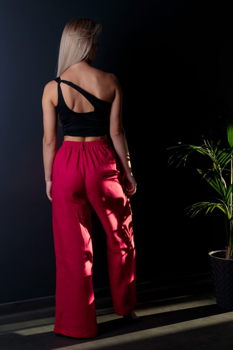 Spodnie damskie lniane viva magenta malinowe na modelce tył czarne tło